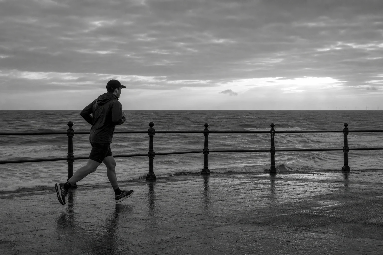 Runner completing an early morning training session on a wet seafront promenade
